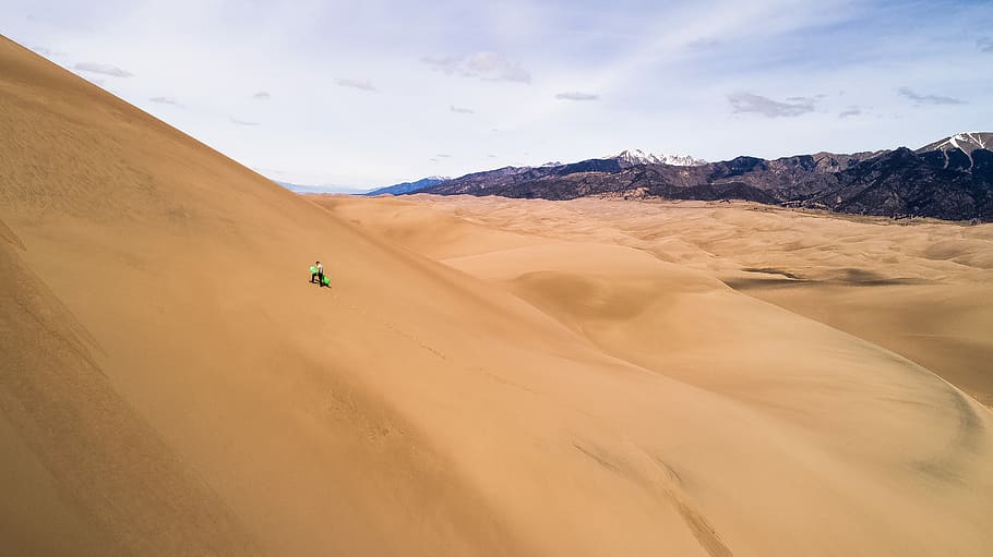 person sits on desert under clear blue sky during daytime, person standing on desert field HD wallpaper