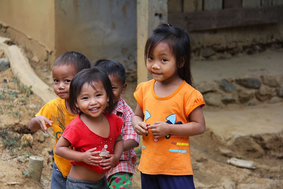 smiling girl in red shirt standing next to girl in yellow shirt and two boys