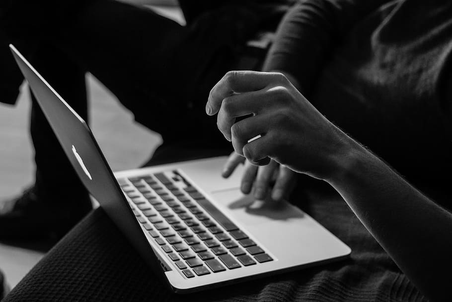grayscale photo of person using MacBook, silver MacBook on person's legs HD wallpaper