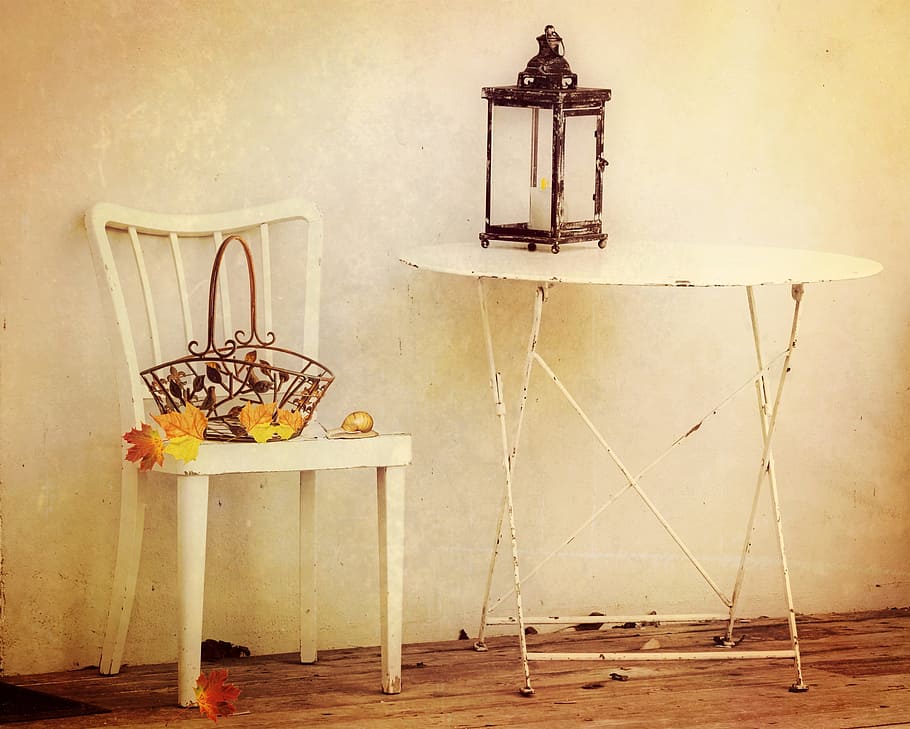 person taking photo of brown candle sconce on white metal folding table near white chair with brown wrought iron basket on top