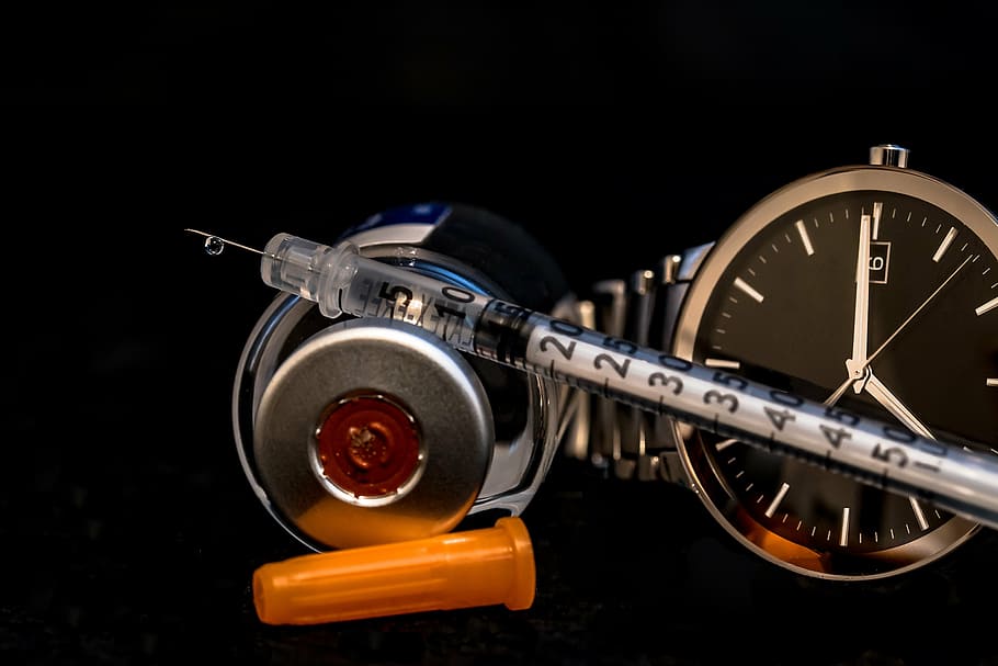 clear syringe beside analog watch with link band, insulin syringe