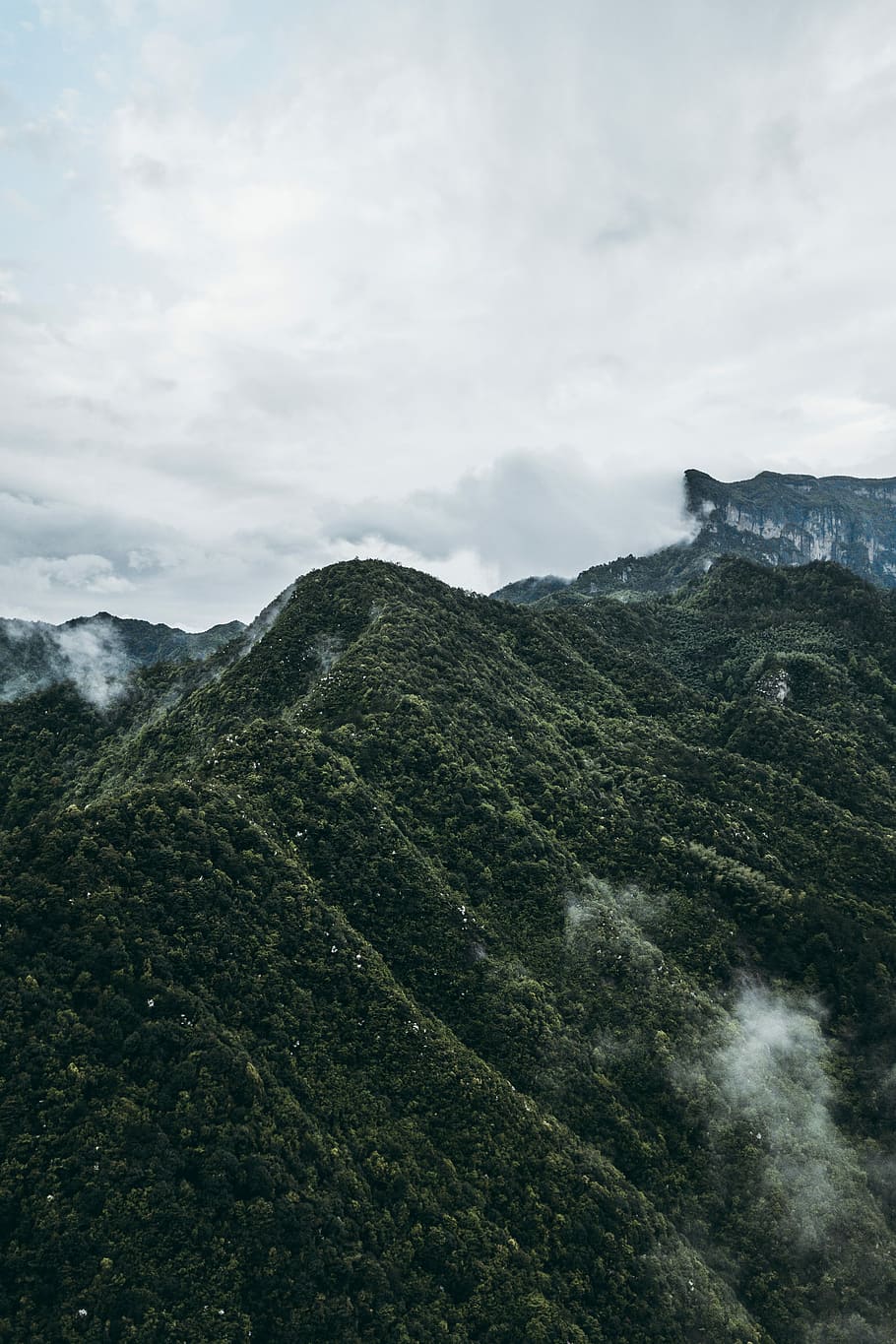 aerial view of hills, close up photography of peak of mountain under clear white and grey sky HD wallpaper