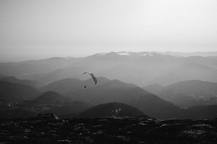 grayscale photography of person paragliding above hills, mountain HD wallpaper