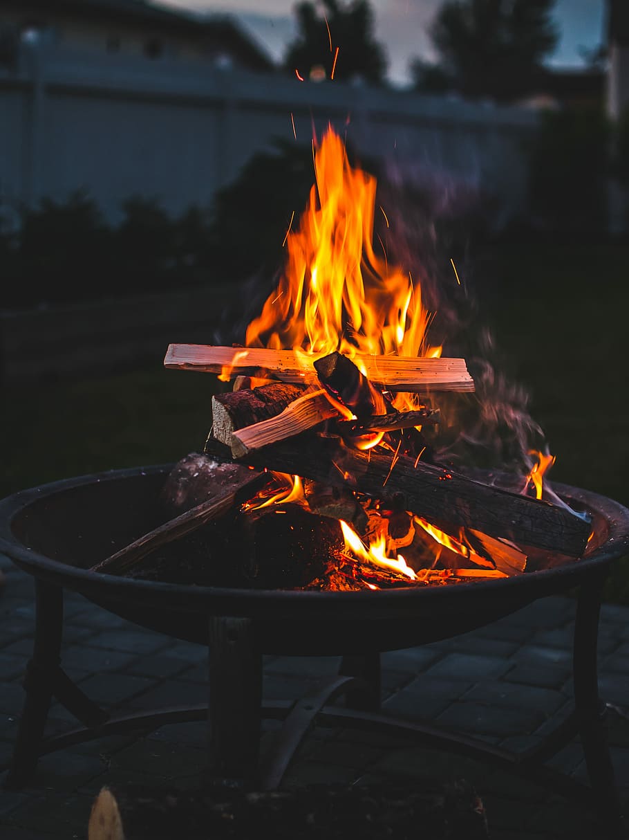 bonfire on brown steel fire pit during sunset, wood burning on fire pit