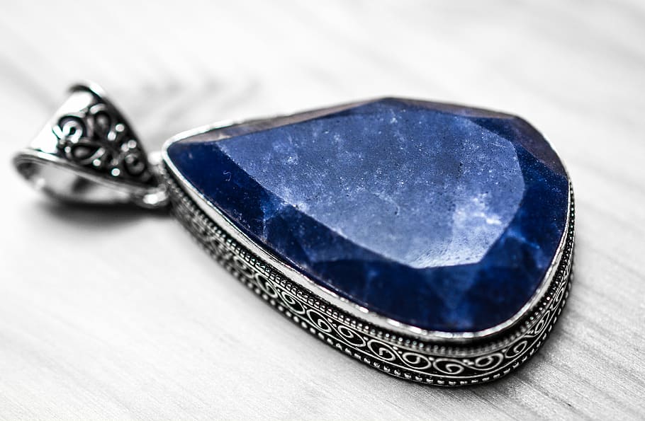 silver and blue pendant on gray wooden table, sapphire, stone