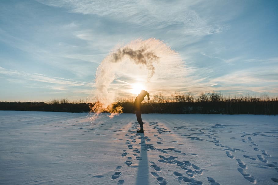 person standing on snowy ground spreading snow on air, person whipping snow during golden hour HD wallpaper