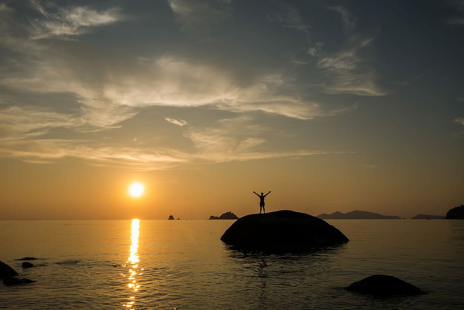 silhouette of man standing on stone near body of water during sunset, HD wallpaper