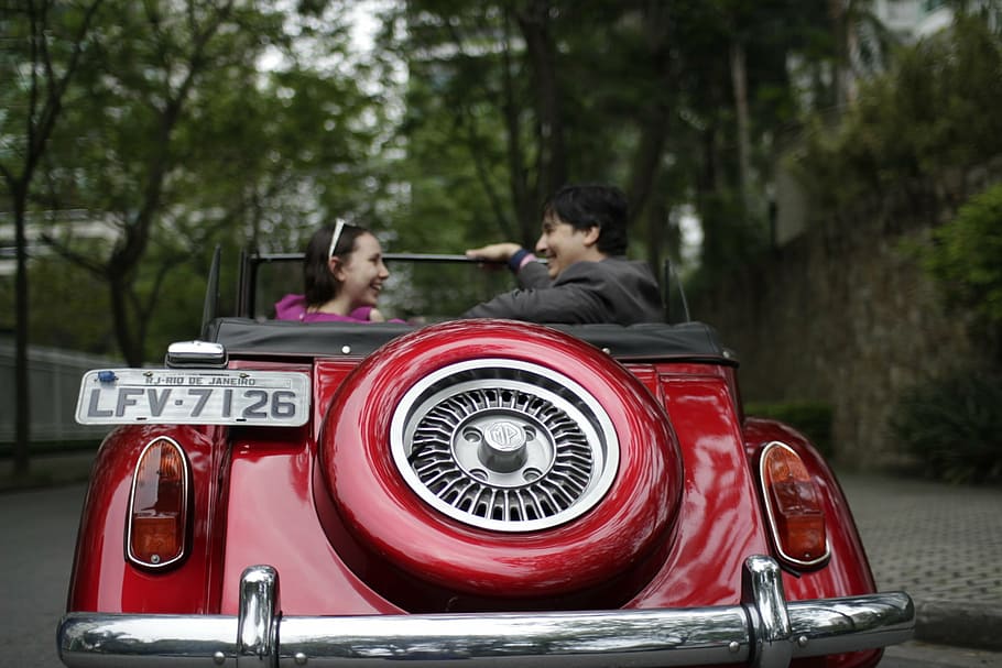 couple riding classic red convertible coupe during daytime HD wallpaper
