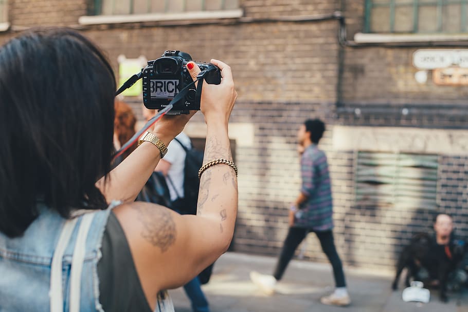 person taking photo on concrete building, person holding camera in front of building HD wallpaper