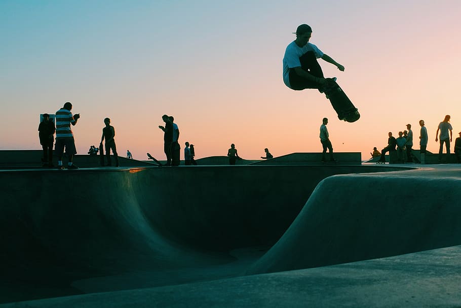 man riding skateboard during golden hour, skateboarding, venue