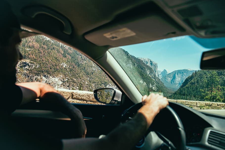 man driving vehicle on road across mountains during daytime HD wallpaper
