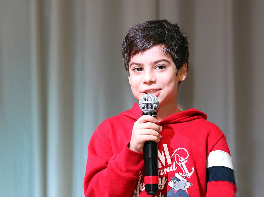 boy wears red hoodie and holds talking white holding black microphone HD wallpaper