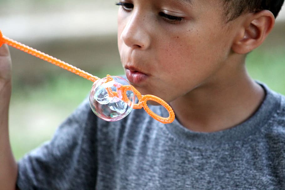 boy playing bubbles in orange plastic stick, soap bubble, blowing HD wallpaper