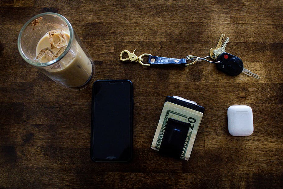 flat lay photogrphy of AirPods, key, wallet, and phone on table
