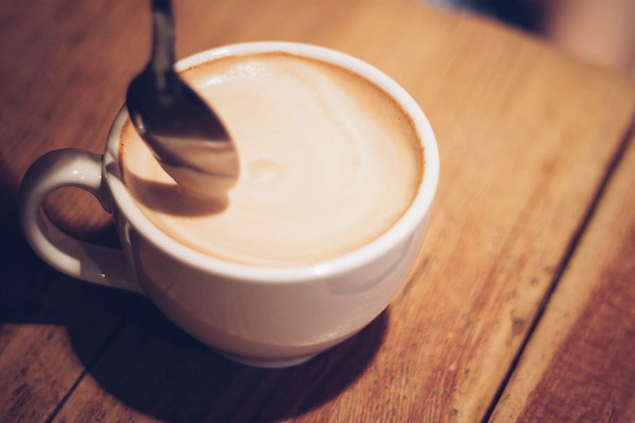 coffee in white ceramic cup and silver-colored spoon placed in brown wood surface HD wallpaper