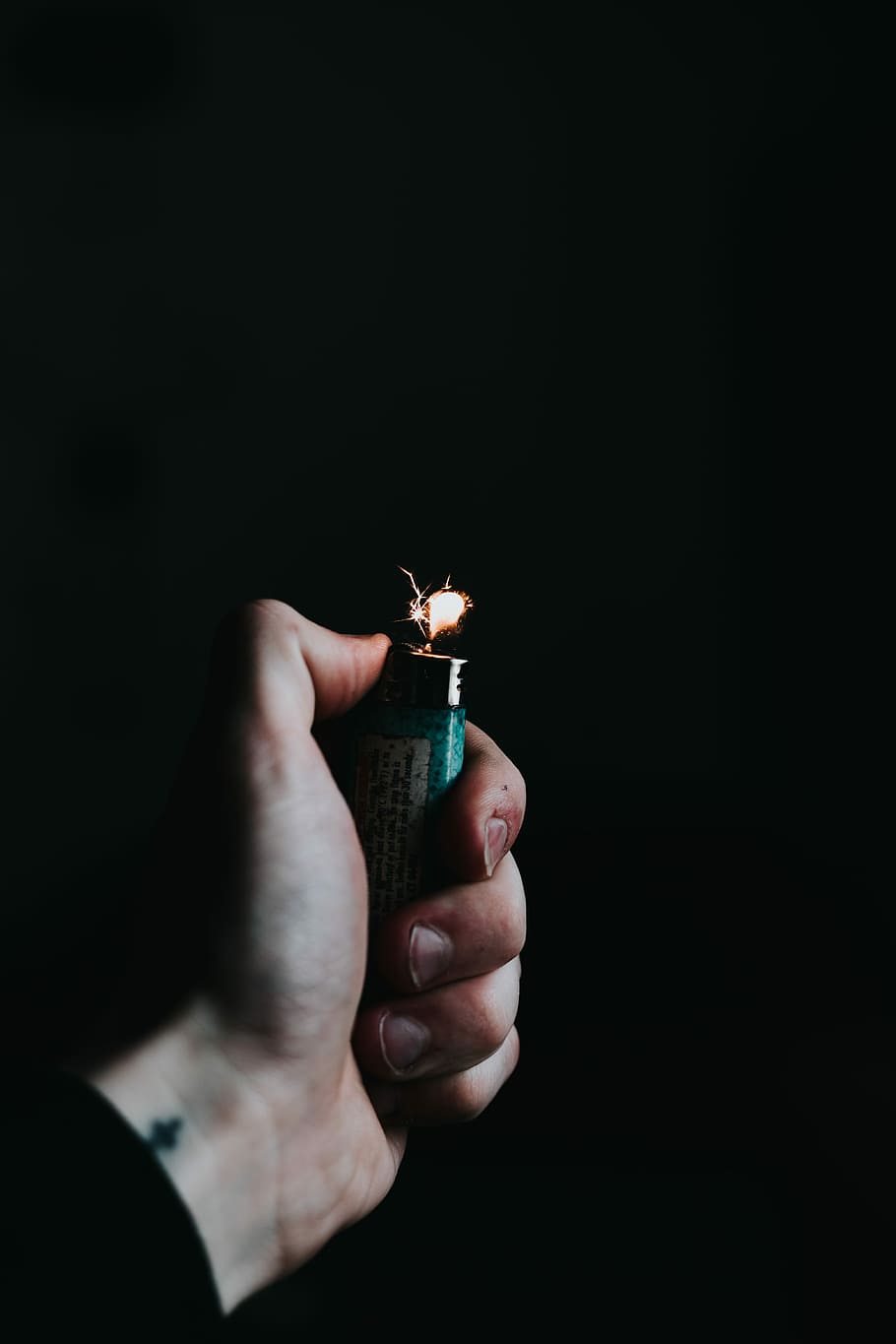 person holding green lighter, person using teal lighter, flame