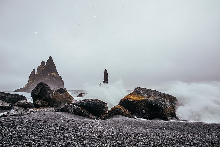 brown and gray rock formation near body of water, black and brown stones beside sea waves during daytime HD wallpaper