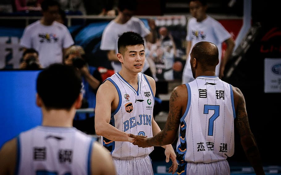 photo of man holding another man's hand, two basketball players hold hands