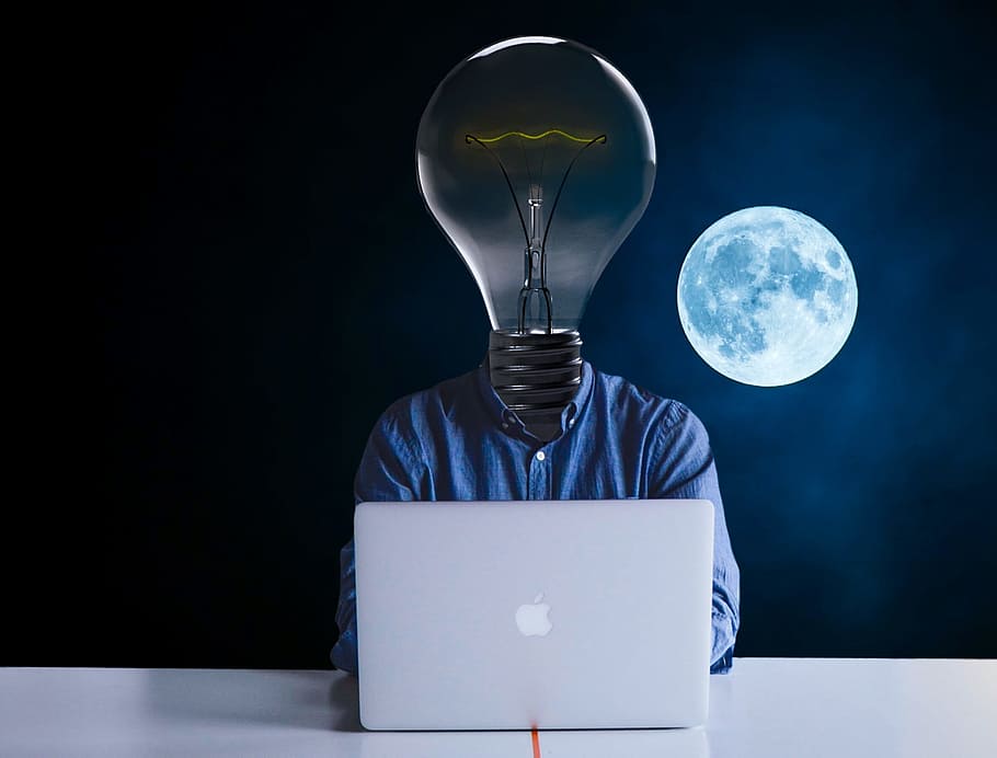 person light-bulb head in front of silver MacBook with full moon background