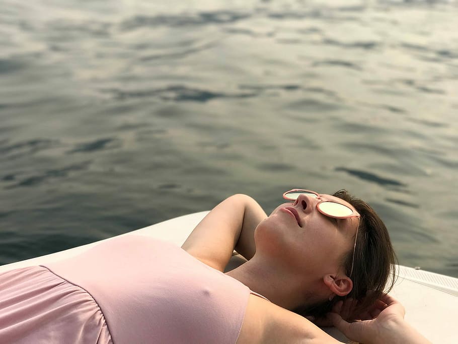woman laying on white surface near body of water, woman lying on white surface near body of water