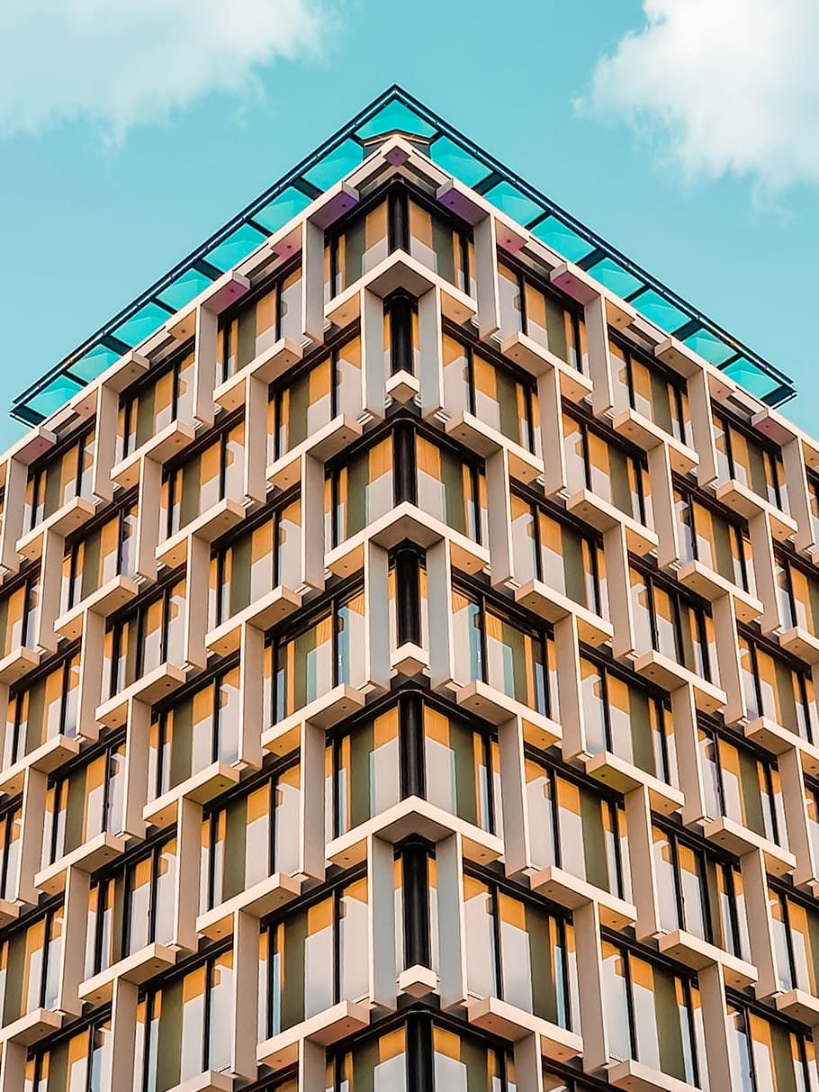 brown and black concrete building under the blue sky during daytime, low angle photo of white and orange architectural building HD wallpaper