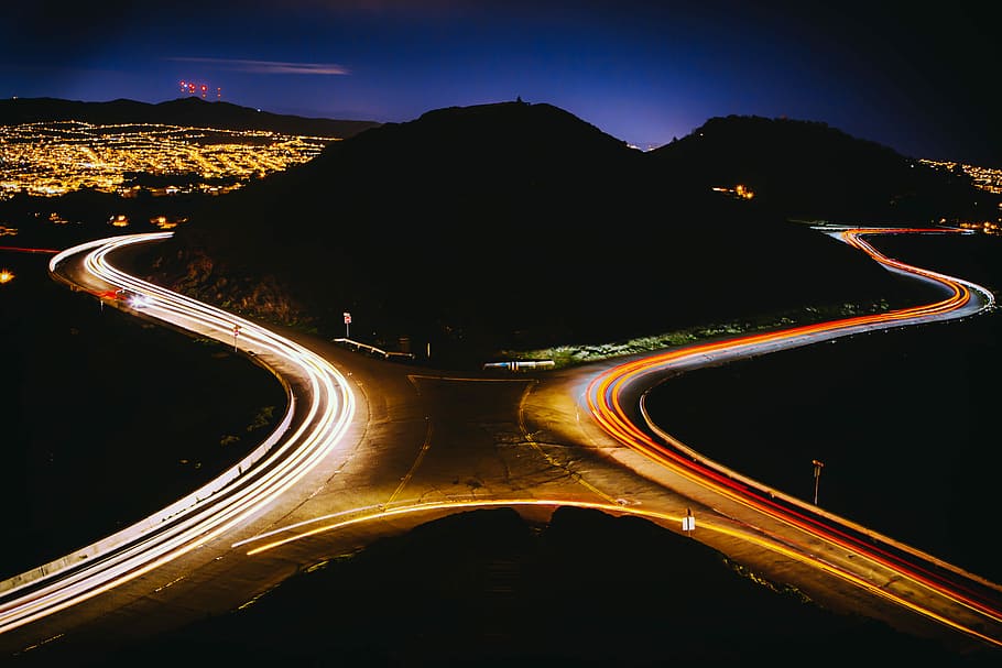 aerial view photography of cross road near mountain during nighttime, hill surrounded by asphalt road during nighttime timelapse photography HD wallpaper