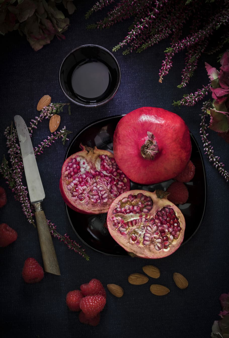 red fruit on black plate, sliced promeganante, pomegranate, seeds