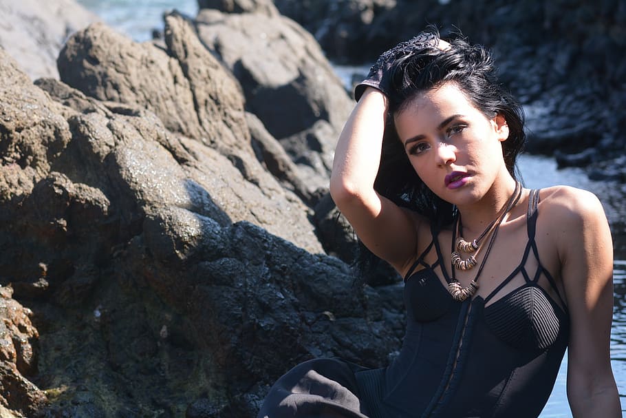 shallow focus photography of woman sitting beside rock boulder HD wallpaper