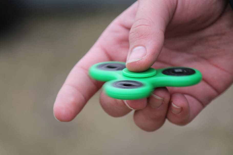 person holding tri-spin fidget toy, fidget spinner, mental health