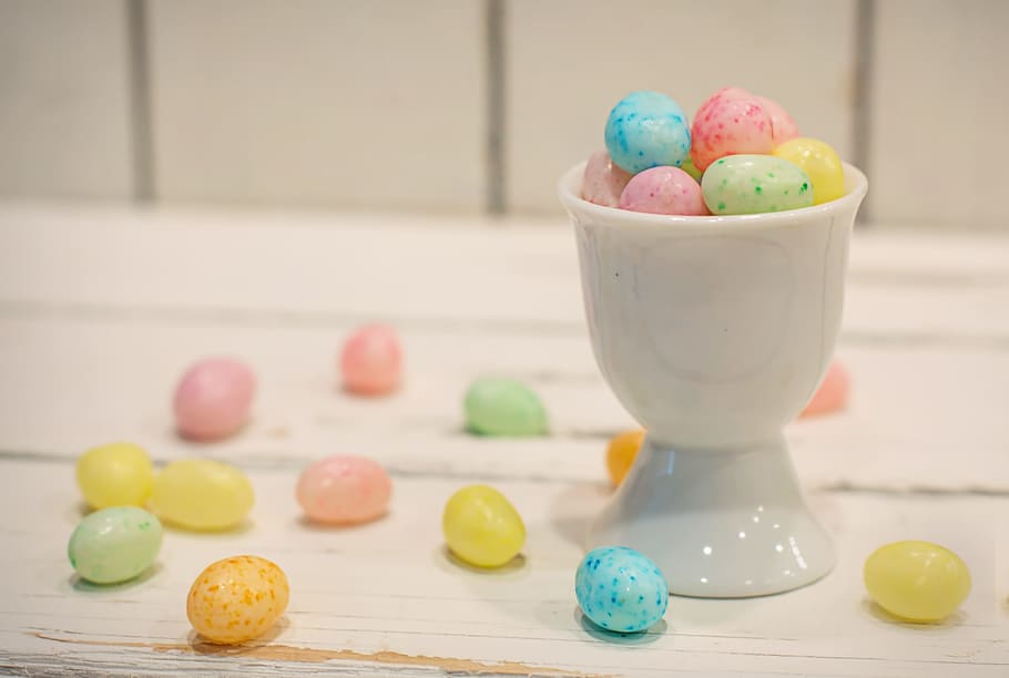 egg candies surrounded beside ceramic footed cup, yellow, blue HD wallpaper