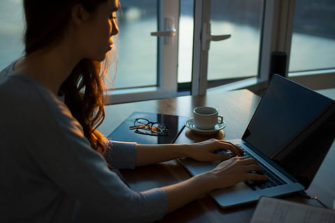 woman sitting beside table using laptop, woman facing in front of laptop computer HD wallpaper