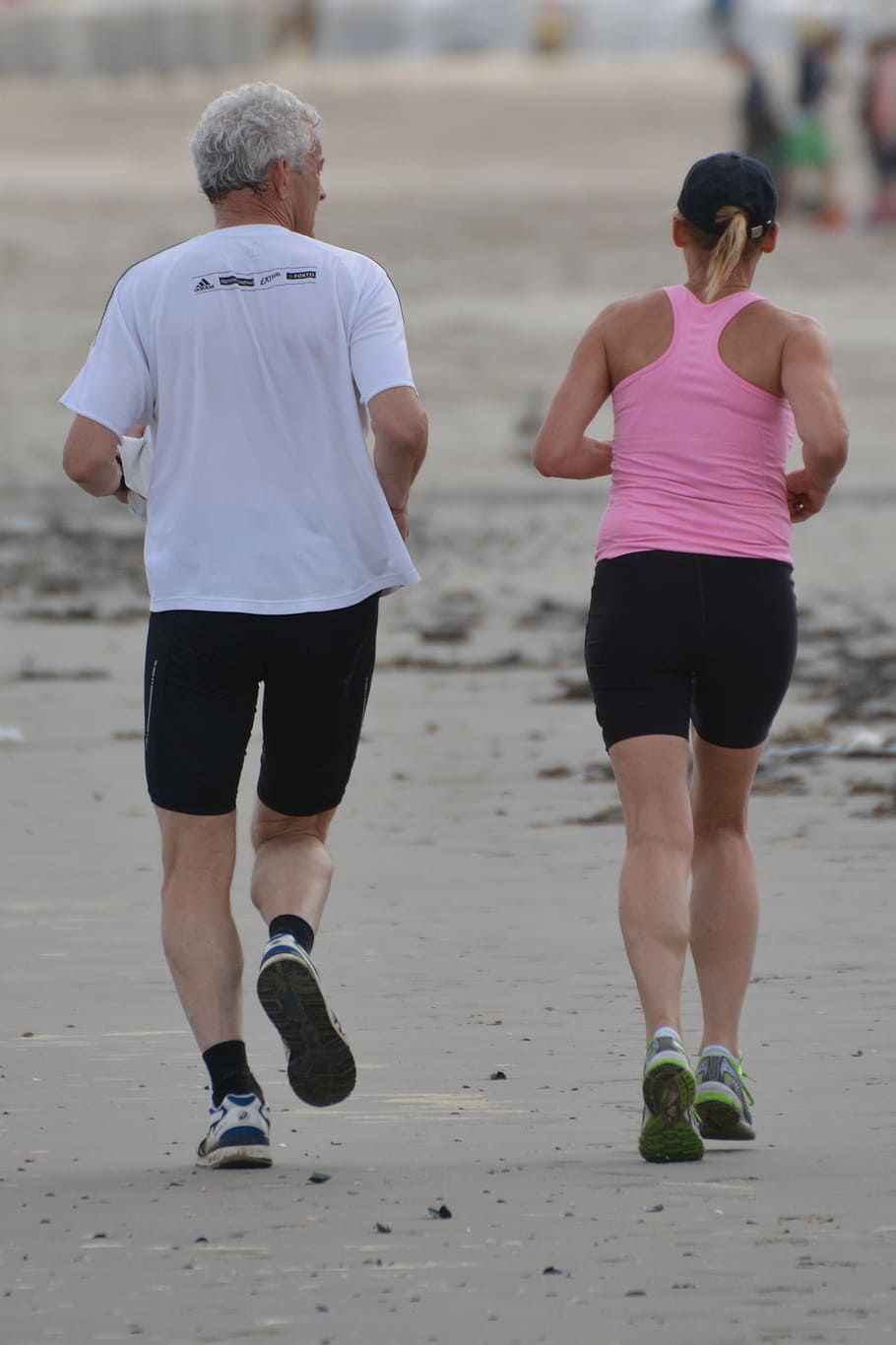 man in white top jogging beside woman in pink racerback top, people