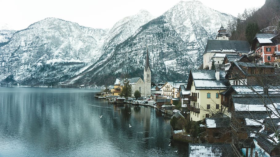 white and brown houses beside body of water and near snow covered mountains at daytime, houses beside beach near mountain alps HD wallpaper