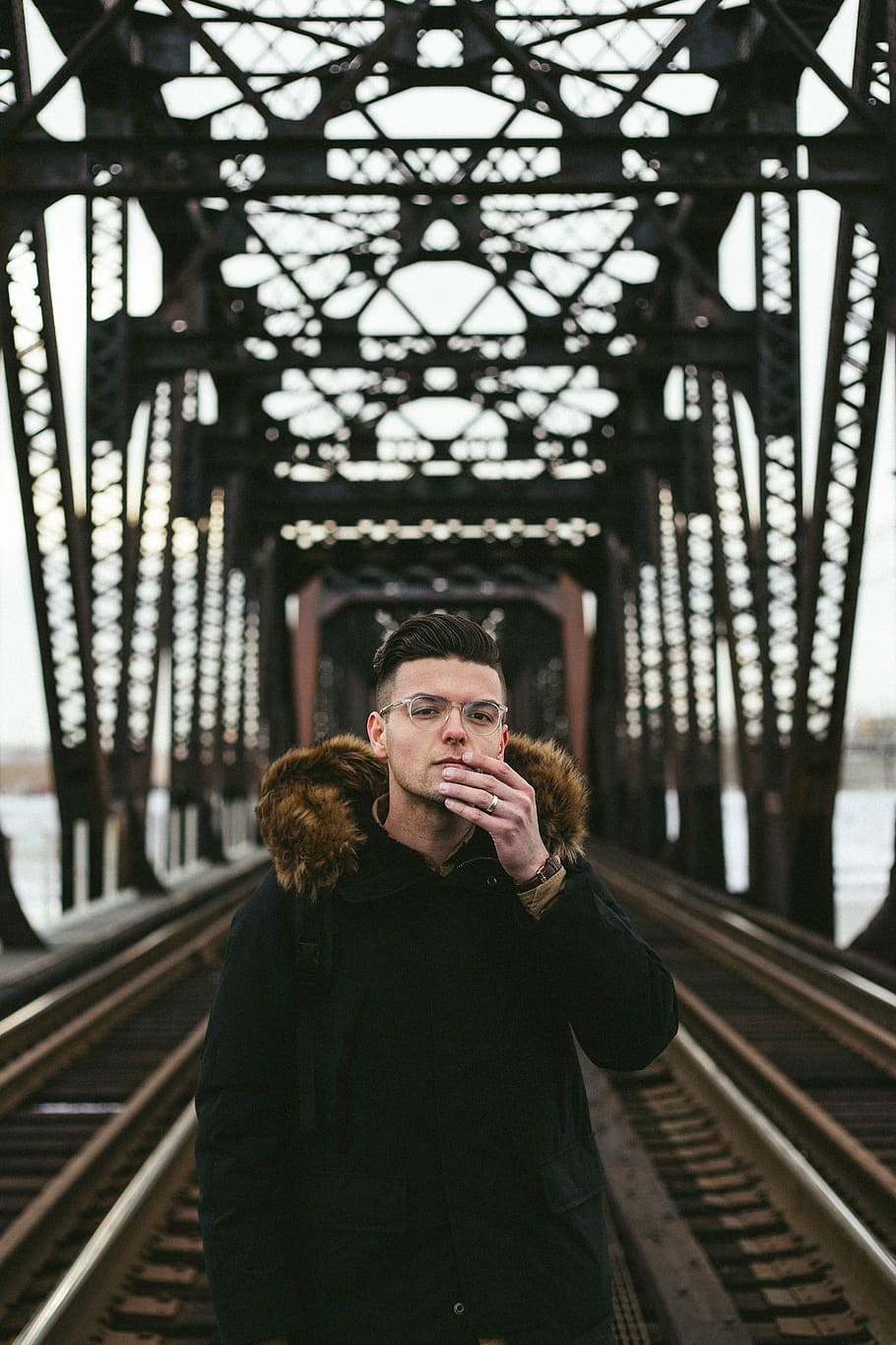 man wearing black fleece coat standing on concrete bridge during daytime HD wallpaper