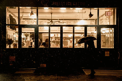 person standing in front of restaurant, woman holding umbrella passing by sidewalk HD wallpaper