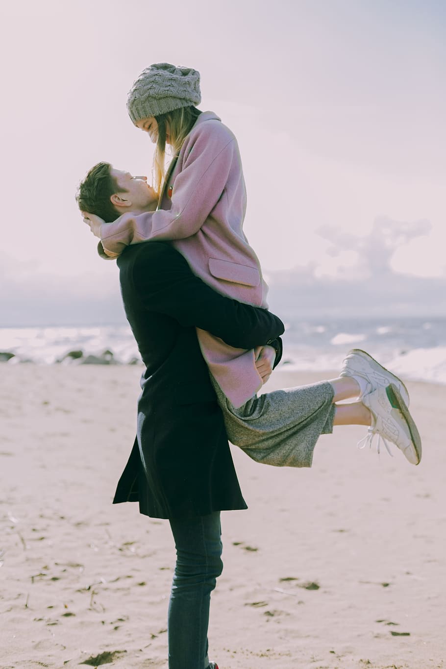 Man in Gray Coat Carrying Woman Wearing Pink Coat in Beach Near Shoreline and Body of Water, HD wallpaper