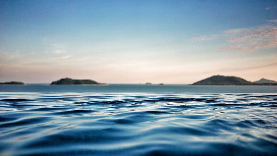 shallow focus photography of ocean with mountain on far side, landscape photo of body of water HD wallpaper