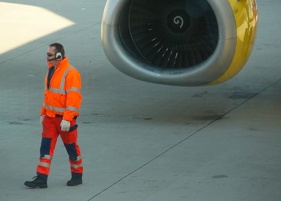 man with white headset walking in front of airplane during daytime HD wallpaper