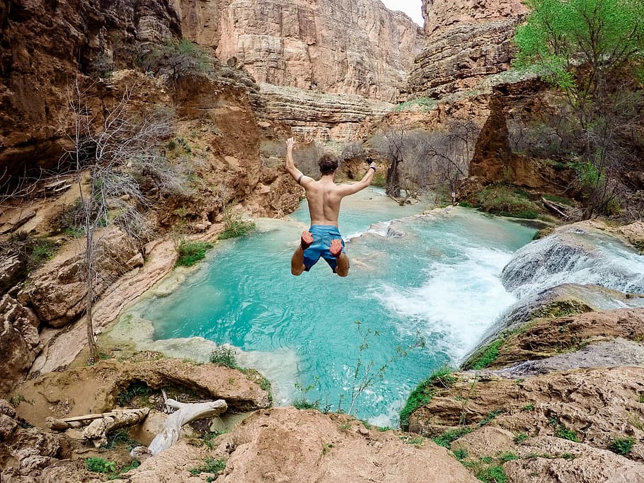 man about to jump on waterfalls at daytime, green, grass, moss HD wallpaper