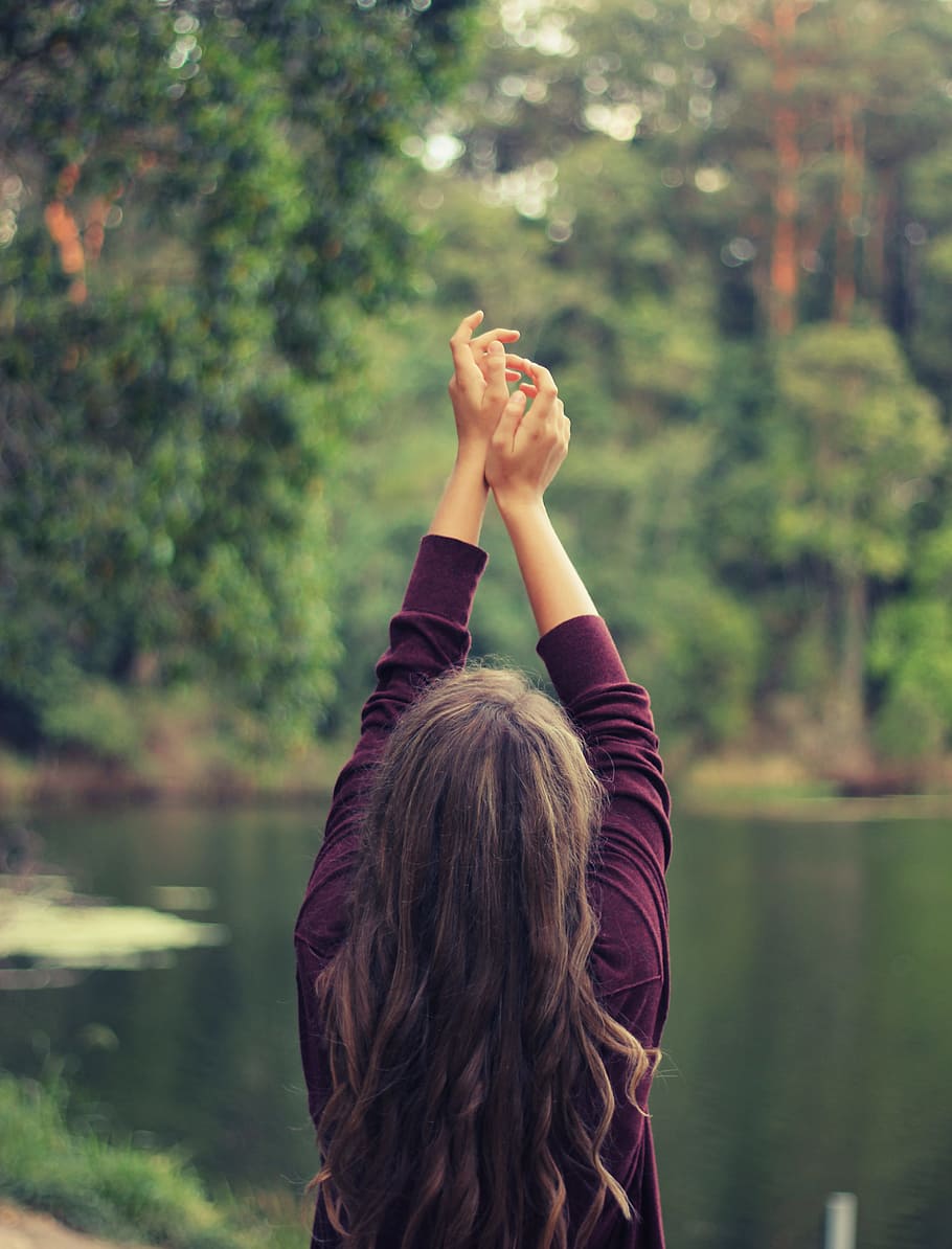 woman raising both of her hands, woman raising her hands on the sky while standing infront of lake