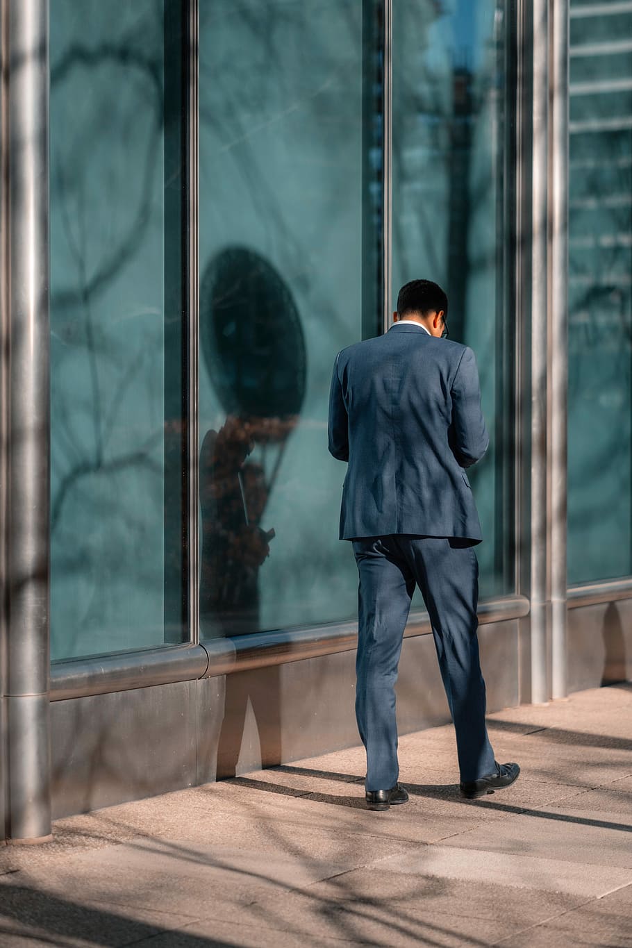 man standing near glass wall, man wearing blue dress shirt and pants near window glass panel HD wallpaper