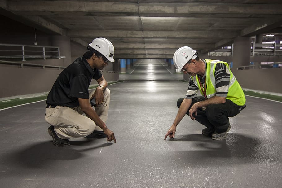 two men pointing grey floor inside underground, onsite, man HD wallpaper