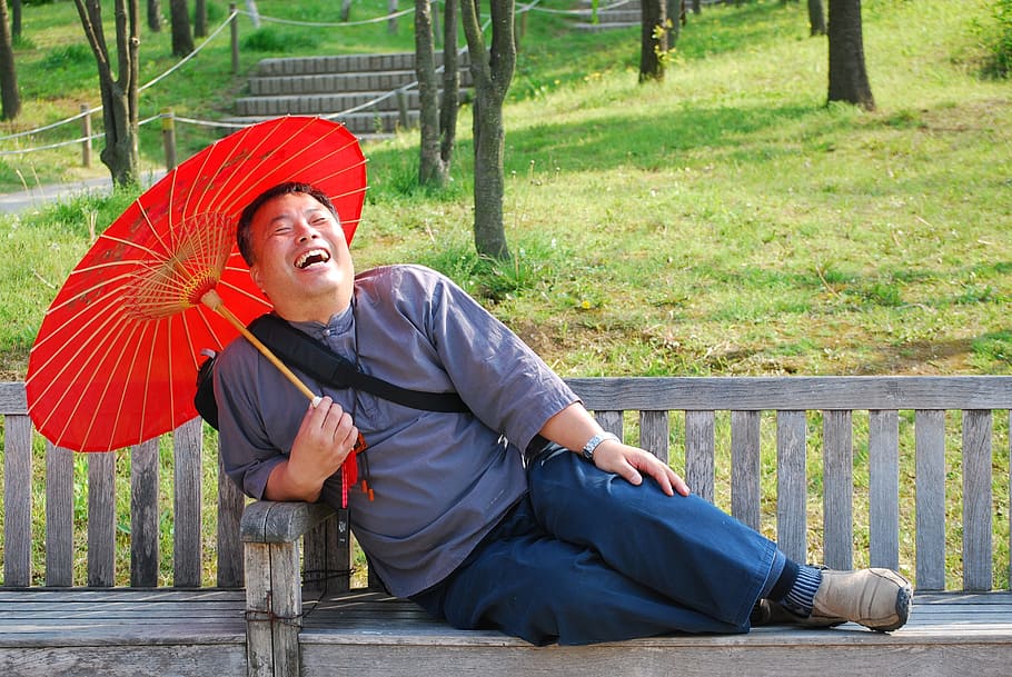 man laughing while sitting on bench holding oil paper umbrella, HD wallpaper