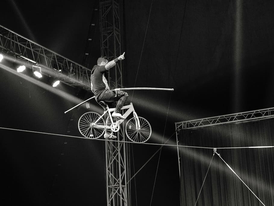 man riding bicycle on cable, rope walker, acrobat, danger, risk
