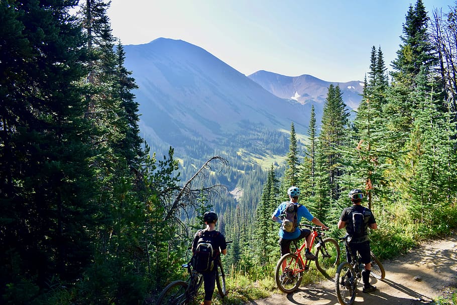 three person riding on bicycles during daytime, three men riding bike besides mountain cliff during daytime HD wallpaper