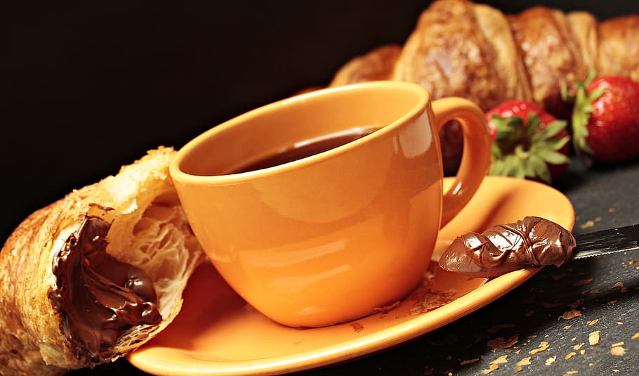 photo of brown ceramic coffee mug on saucer, croissant, strawberries