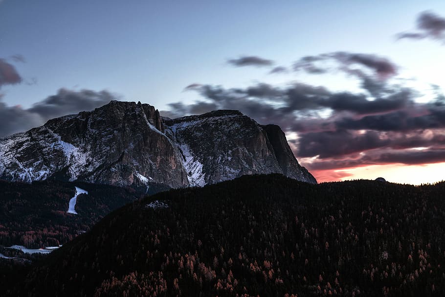 photo of snowy mountain, white and black rocky mountain with distance to forest under blue and white sky HD wallpaper
