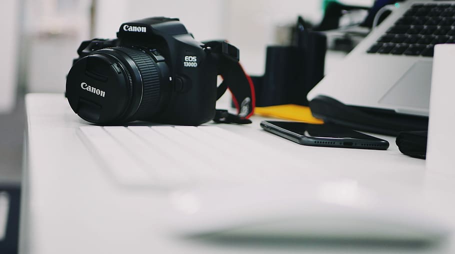 selective focus photography of DSLR camera beside keyboard, selective focus photography of black Canon DSLR camera