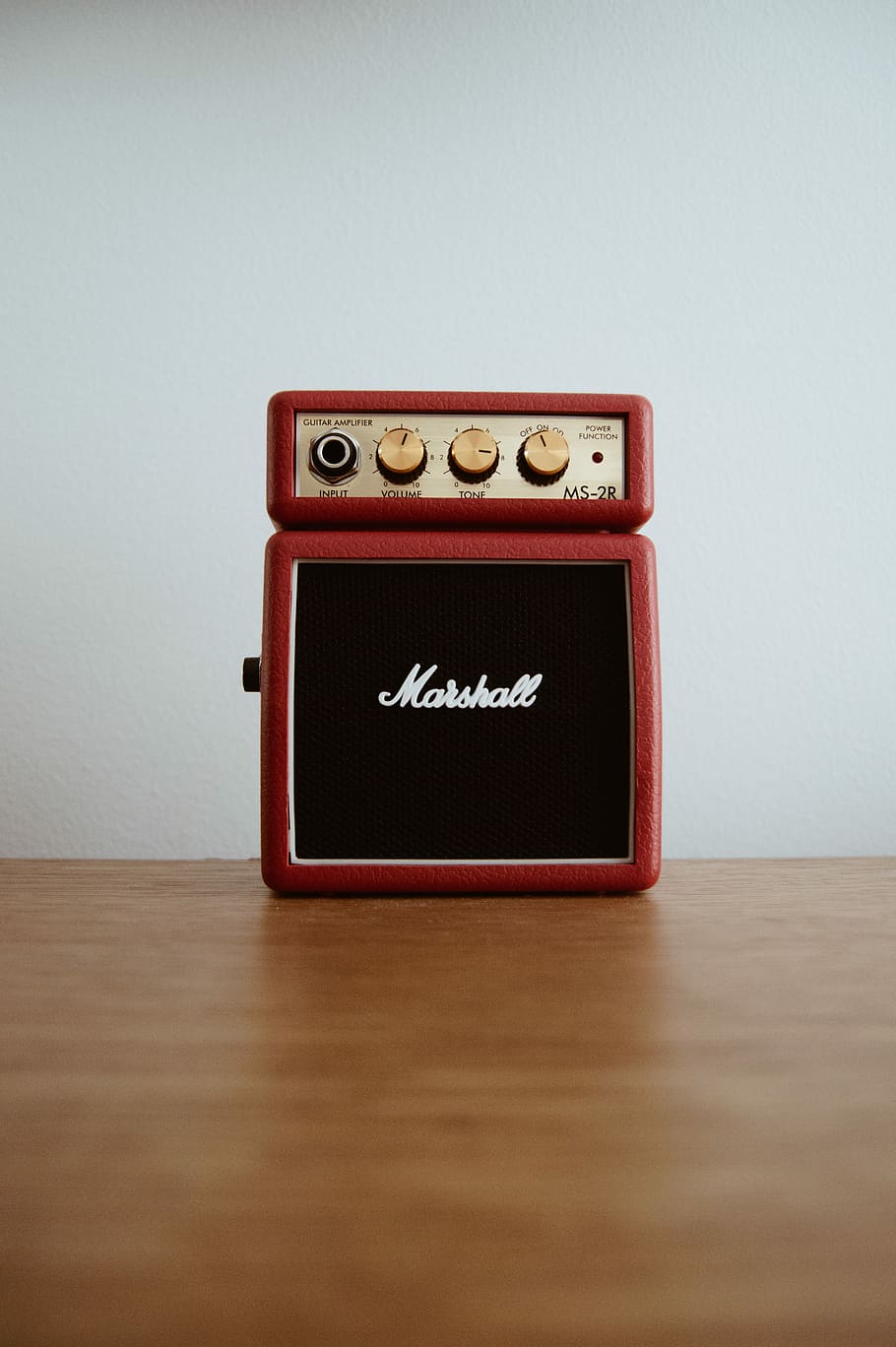 photo of brown Marshal guitar amplifier on brown board, red Marschall guitar amplifier on brown wooden surface