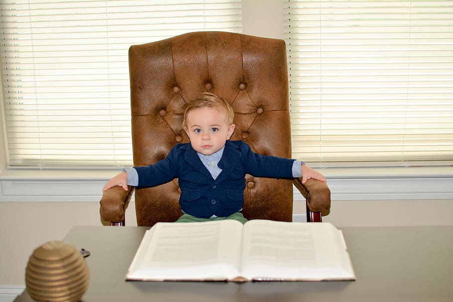 boy sitting on office chain in front of book, toddler, ceo, child, HD wallpaper